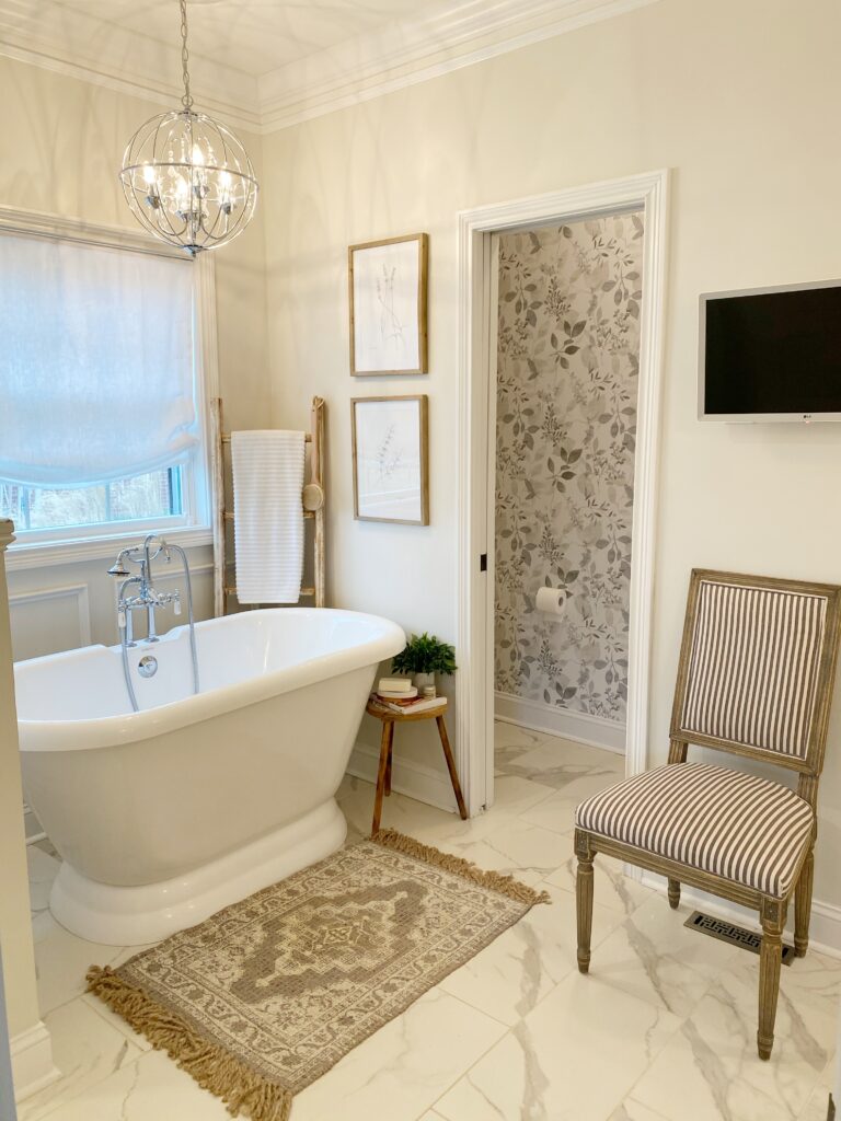 Freestanding bathtub, TV on wall and accent chair with view of new peel and stick wallpaper