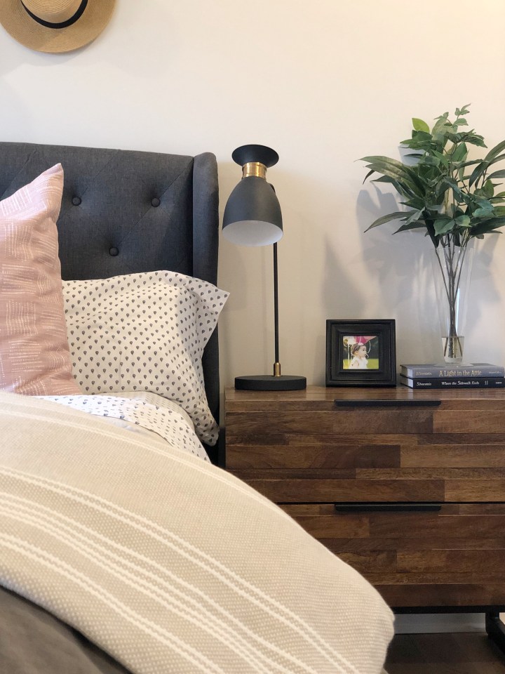 upholstered headboard in a dark gray with wood and metal nightstand.